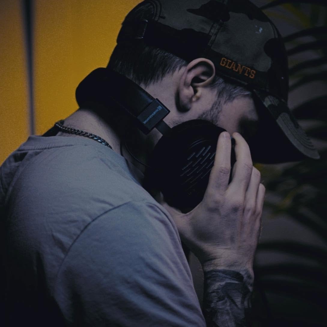 VOIDSHADE holding headphones, wearing a cap